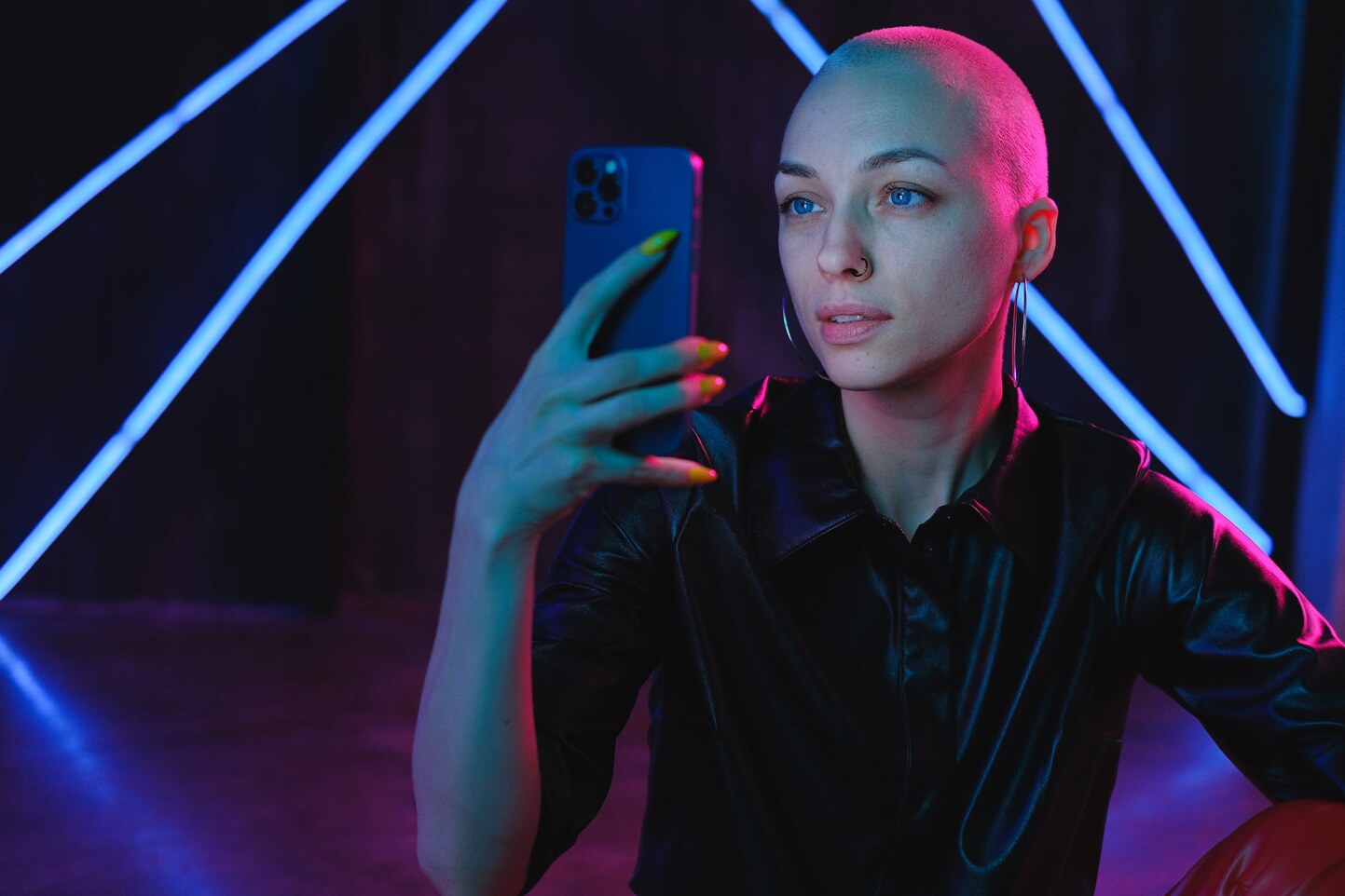 Creator holding a phone under blue and magenta studio lighting.